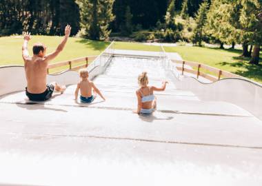 Familie auf Wasserrutsche im Waldschwimmbad