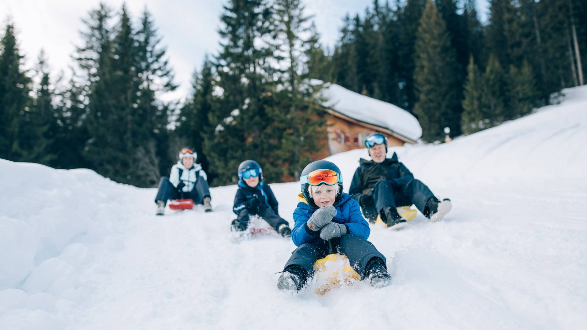 Familie beim Rodeln in Oberlech